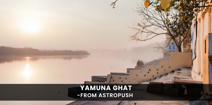 Scenic view of Yamuna Ghat with boats, serene waters, and devotees performing rituals at sunrise.